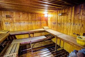 Sauna im SBH Club Paraiso Playa mit hölzernen Bänken und einer gelben Holzwanne.
