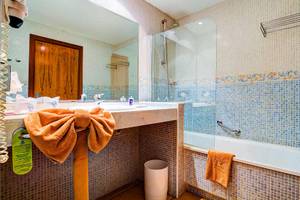 Badezimmer im SBH Club Paraiso Playa Hotel mit blauen Fliesen und Badewanne.