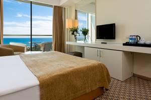 Hotelzimmer im Crystal Centro Resort mit Meerblick, einem großen Bett, Schreibtisch und Fernseher.