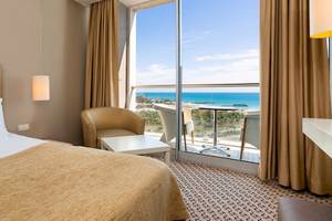 Hotelzimmer mit Meerblick im Crystal Centro Resort mit Bett, Sessel, Tisch und Panoramafenster.