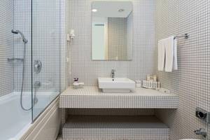 Badezimmer im Crystal Centro Resort mit Badewanne, Dusche, Spiegel und Waschbecken.