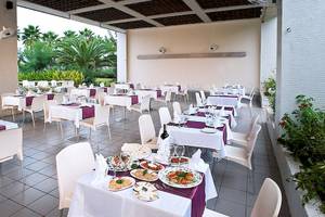 Terrasse des Crystal Centro Resorts mit vielen gedeckten Tischen und Essensplatten.