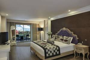 Schlafzimmer des Delphin Imperial Hotels mit großem Bett, Fernseher und Balkon