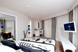 Schlafzimmer im Delphin Imperial Hotel mit Bett, Fernseher, Schreibtisch und Lampe