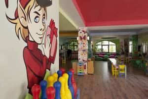 Kinderspielzimmer im Delphin Imperial Hotel mit Bowling-Kegel, bunten Möbeln und Wandmalerei.