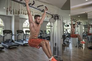 Ein Mann trainiert im Fitnessstudio des Delphin Imperial Hotels mit Klimmzugstangen.