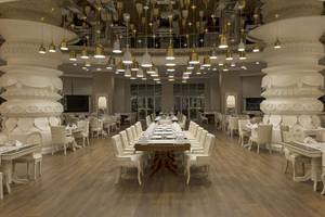 Innenansicht des Restaurants im Delphin Imperial Hotel mit weißen Säulen und hängenden Kronleuchtern.