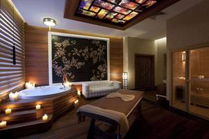 Spa-Bereich im Delphin Imperial Hotel mit Badewanne, Liege, Deko und Beleuchtung.