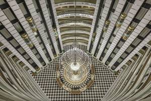 Ansicht von oben des Delphin Imperial Hotel-Lobbys mit zentralem Kronleuchter und schwarzen und weißen Bodenfliesen.