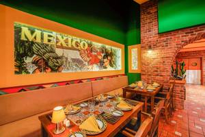 Inneneinrichtung eines mexikanischen Thema-Restaurants mit einem großen Wandbild von Mexiko und gedeckten Tischen.