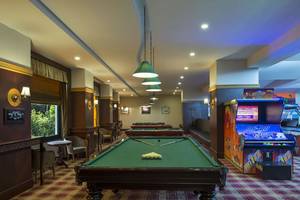 Spielzimmer im Delphin Palace Hotel mit Billardtischen und Arcade-Spielautomaten.