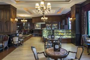 Innenbereich des Delphin Palace Hotels mit hölzernen Wänden, Kronleuchtern und Tischen.