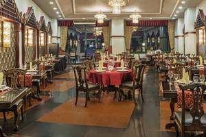 Innenansicht des Restaurants Delphin Palace mit gedeckten Tischen und hängenden Kronleuchtern.