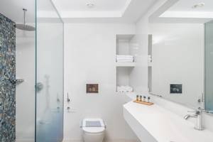Badezimmer im Lyttos Mare Hotel mit Glasdusche, Toilette und Waschbecken.