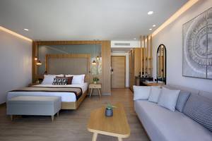 Innenansicht des Schlafzimmers im Lyttos Mare Hotel mit Doppelbett, Sofa, Tisch und Dekor.