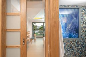 Innenansicht eines Zimmers im Hotel Lyttos Mare mit offenem Holztür, Holzmöbel und Ausblick auf Garten
