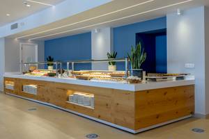 Buffet-Tisch im Lyttos Mare Hotel mit verschiedenen Gerichten und Pflanzen in der Nähe.