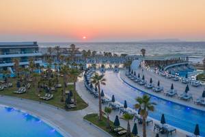 Lyttos Mare Hotel mit Sonnenuntergang am Strand und Swimmingpools.