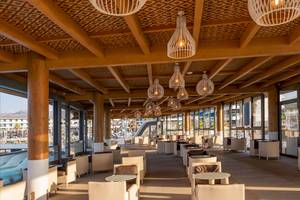 Lounge-Bereich des Lyttos Mare Hotels mit Holzmöbeln und hängenden Lampen.