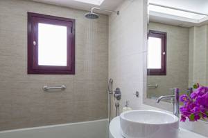 Badezimmer im Veggera Hotel mit Badewanne, Dusche, Waschbecken und Spiegel.