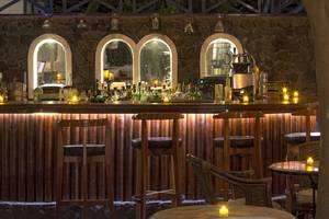 Innenansicht der Bar im Veggera Hotel mit Holzbar, Stühlen, Tischen und brennenden Kerzen.