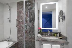 Badezimmer im Hilton Hurghada Plaza Hotel mit Badewanne, Dusche, Spiegel und Waschbecken.