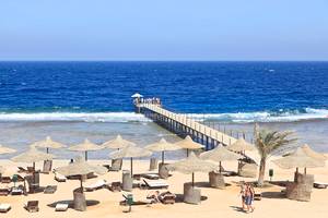 Strand des Three Corners Sea Beach Resorts mit Pier und Sonnenschirmen