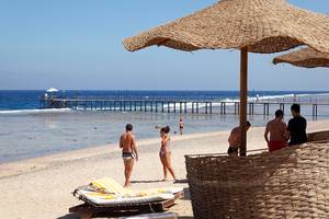 Drei-Ecken-Meeresstrand-Resort Strandansicht mit Menschen und Sonnenschirmen.