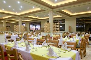 Restaurant des Three Corners Sea Beach Resorts mit gedeckten Tischen und Stühlen.