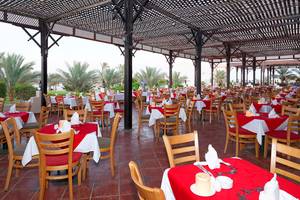 Restaurant im Drei Ecken Meer Strand Resort mit vielen Tischen und Stühlen, teilweise mit roten Tischdecken.