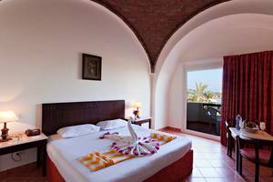 Zimmer im Three Corners Sea Beach Resort mit Bett, Tisch, Lampe und Meerblick.