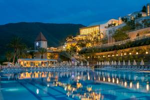 Nachtansicht des Duja Bodrum Hotels mit einem großen Pool und vielen Liegen.