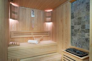 Eine hölzerne Sauna des Duja Bodrum Hotels mit einer Bank, einem Eimer und einem Thermometer an der Wand.