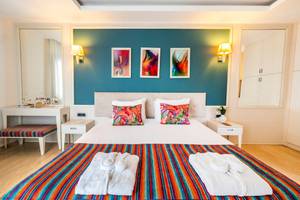 Innenansicht eines Schlafzimmers im Duja Bodrum Hotel mit farbenfrohem Bett und Dekor.