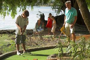Familie spielt Minigolf im Maritim Resort & Spa Mauritius mit Blick auf den Ozean