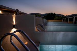 Nachtansicht des Swimmingpools des CHC Galini Palace Hotels mit eingeschalteten Lichtern und dunklem Himmel.