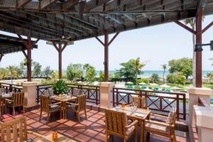 Terrasse des InterContinental Muscat mit Blick auf das Meer und eine Reihe von Tischen und Stühlen.