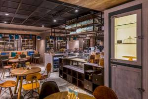 Innenansicht des Cafes im Intercontinental Muscat mit Tischen, Stühlen und Holzelementen.