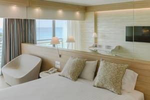 Hotelzimmer mit Meerblick im Mediterranean Hotel - Rhodos, mit Bett, Kissen, Lampe, Telefon, und Aussicht aufs Meer.
