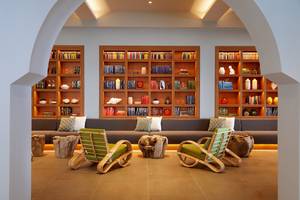 Loungebereich im MarBella Corfu Hotel mit Holzmöbeln und Bücherregalen.