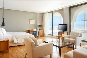 Innenansicht einer Hotelsuite im MarBella Corfu mit Bett, Schreibtisch und Fernseher auf dem Balkon.