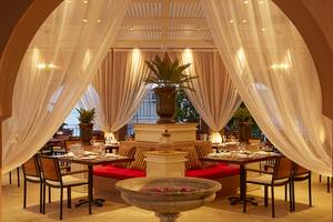 Innenbereich des MarBella Corfu Hotels mit gedeckten Tischen, weichen Vorhängen und Pflanzen.