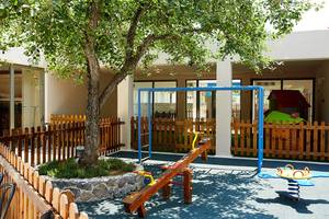 Spielplatz im Freien des MarBella Corfu Hotels mit Schaukeln und Spielhaus.