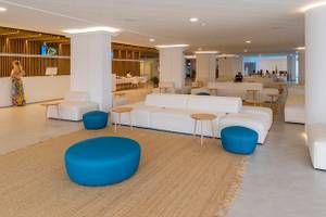 Lobby des Vibra Algarb Hotels mit weißen Möbeln, blauen Hockern und einer Rezeption.
