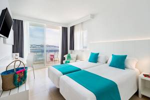 Doppelzimmer im Vibra Algarb Hotel mit Meerblick, zwei Betten, türkisen Kissen, Balkon mit Stühlen und Tisch.