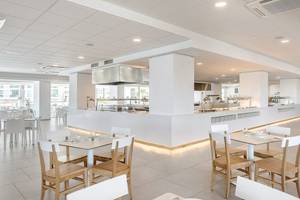Innenbereich des Vibra Algarb Hotels mit hellen Tischen und Stühlen, modernem Design und zentraler Küche.