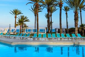 Schwimmbad am Strand des Vibra Algarb Hotels mit blauen Sonnenliegen und Palmen