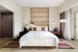 Zimmer im Khalidiya Palace Rayhaan by Rotana mit Bett, das gerade zugedeckt wird