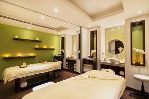 Spa-Behandlungsraum im Khalidiya Palace Rayhaan by Rotana mit zwei Massagetischen, grünen Wänden und Beleuchtung.