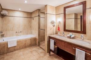 Badezimmer im Khalidiya Palace Rayhaan by Rotana mit Badewanne, Dusche, Spiegel und Waschbecken.